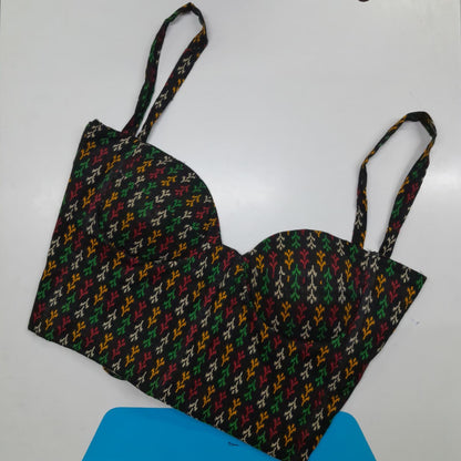 A bustier-style bra top with a multicolor geometric pattern on a black base, featuring thin shoulder straps, laid flat on a white surface.