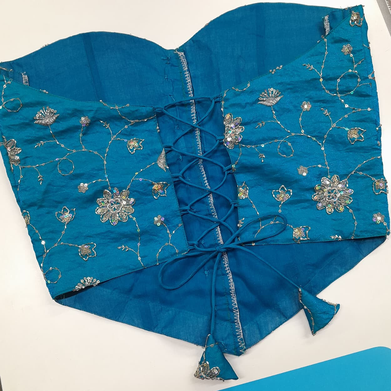 A teal blue embroidered corset bustier with silver floral embroidery and lace-up back detailing, laid flat on a white surface.