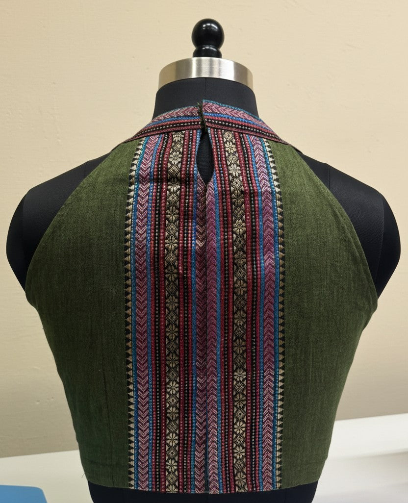Green garment with intricate pattern on a mannequin against a beige background