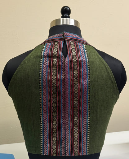 Green garment with intricate pattern on a mannequin against a beige background